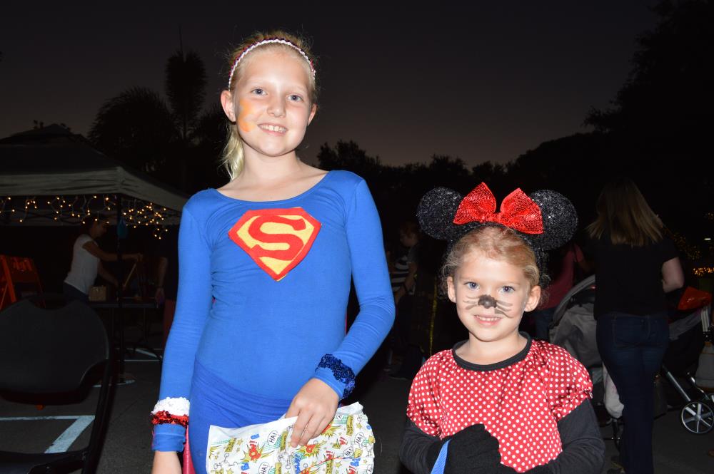 Girl dressed in blue superman outfit stands next to girl dressed in Minnie Mouse outfit